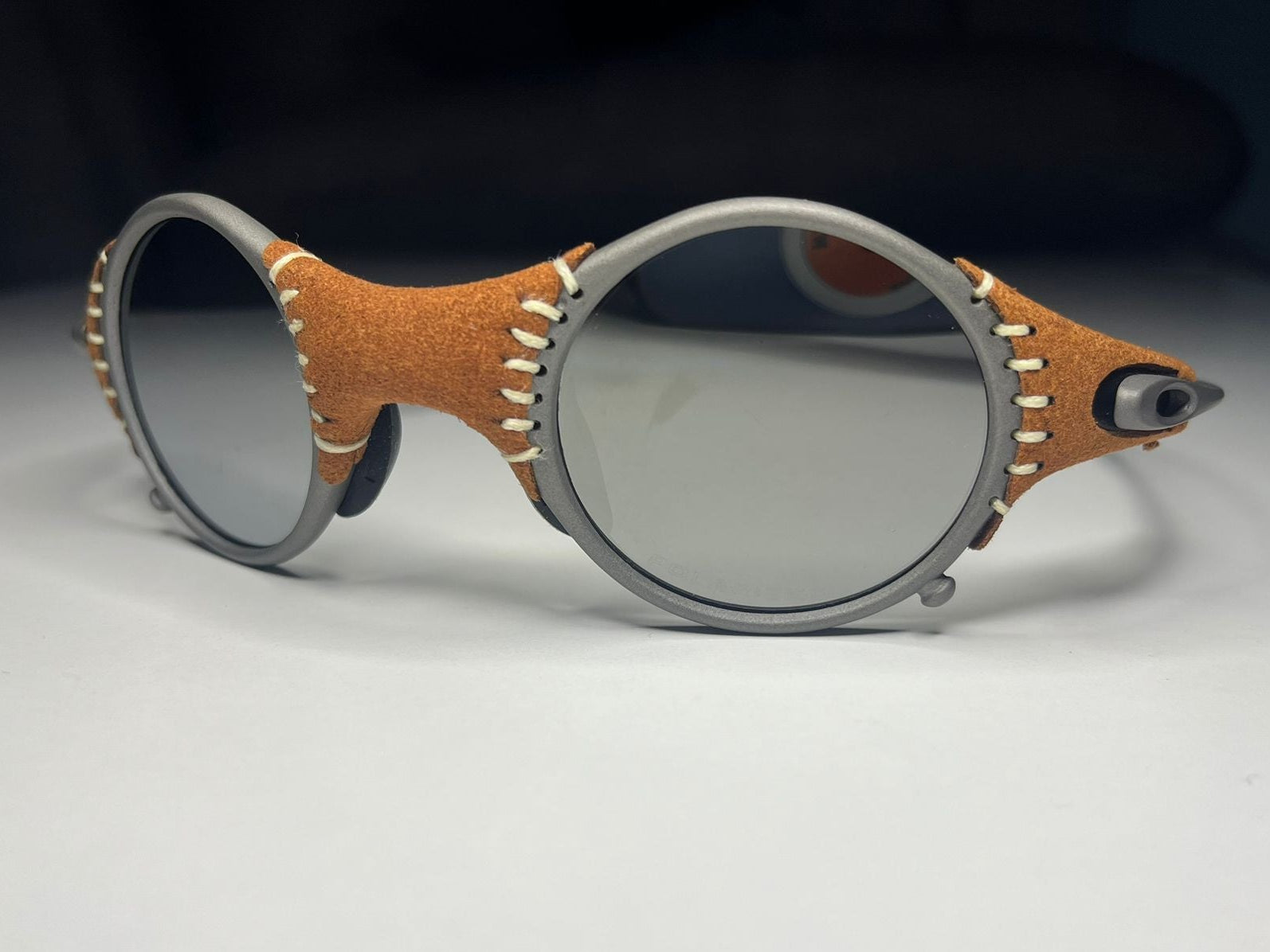 Sunglasses with brown leather and metal frame on a light gray background
