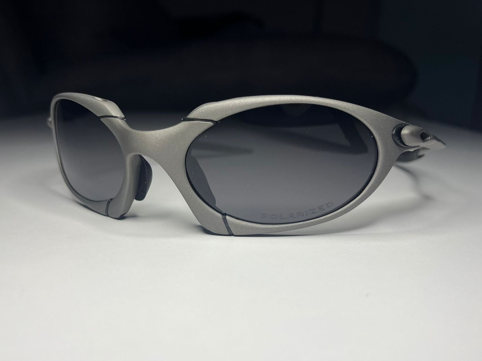Silver sunglasses with dark lenses on a white surface