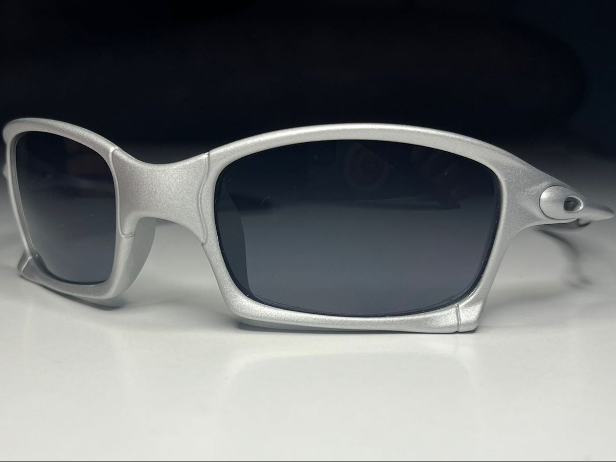 Silver-framed sunglasses with dark lenses on a light gray background