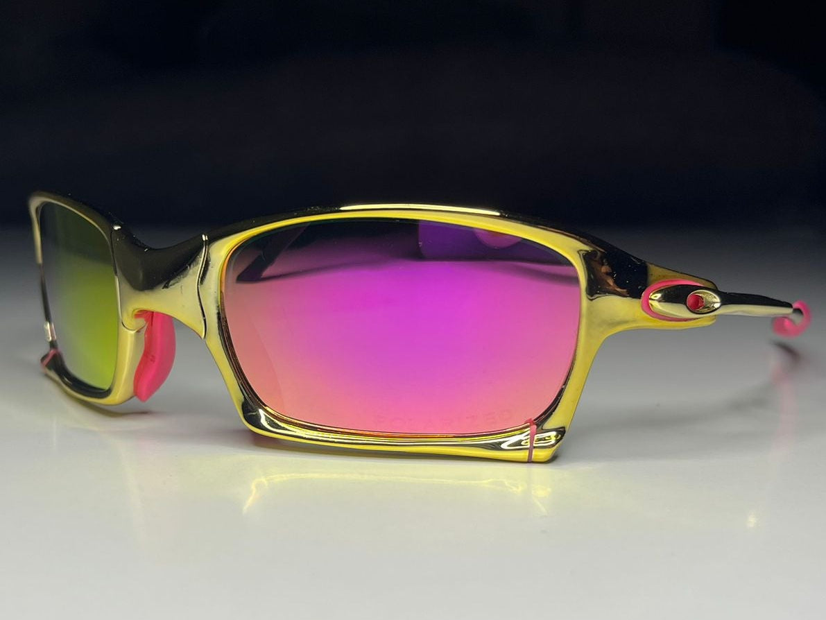 Sunglasses with gold frame and pink lenses on a white surface