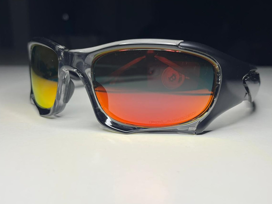 Sunglasses with red and yellow gradient lenses on a white surface