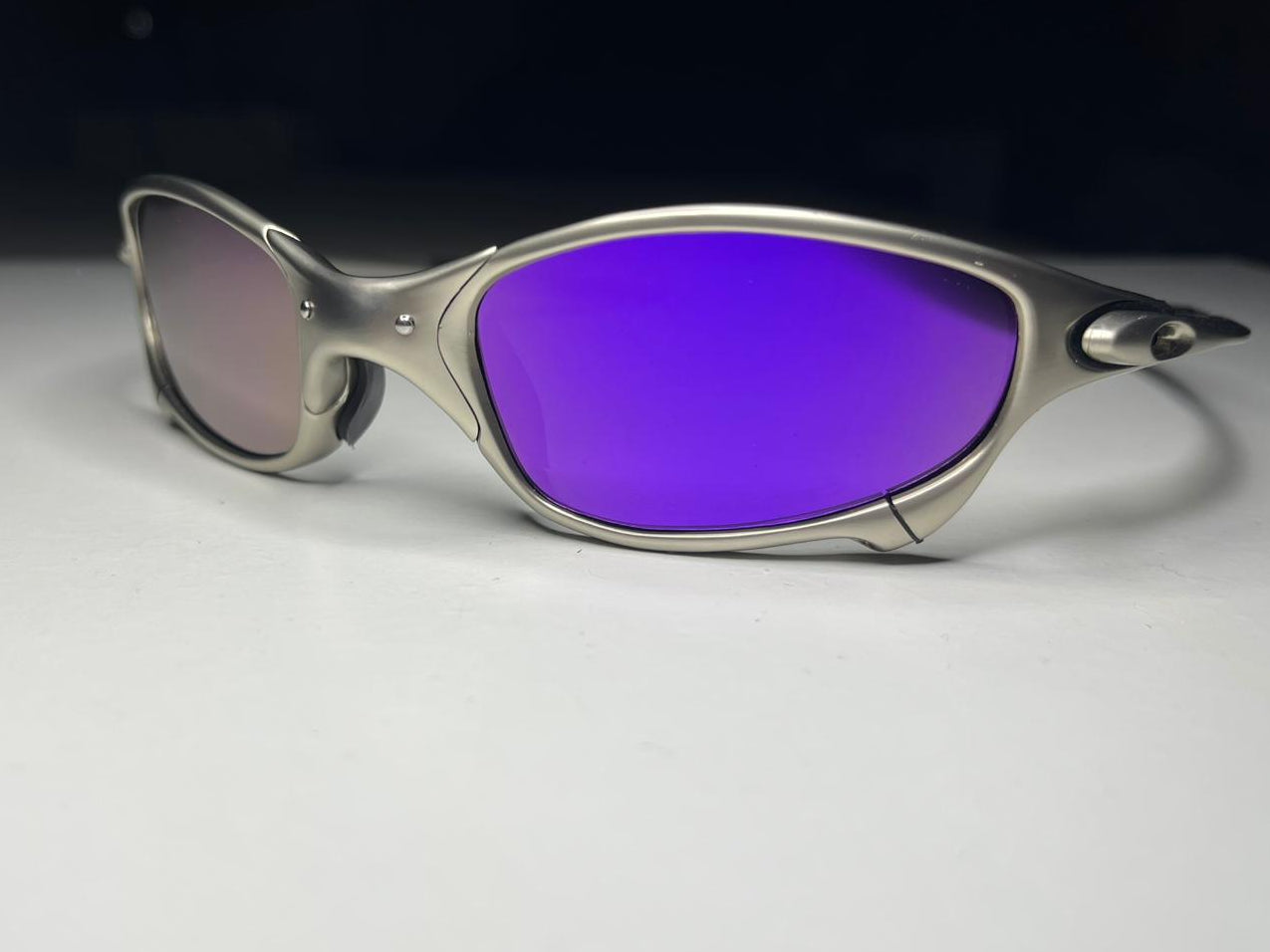 Sunglasses with purple lenses and silver frame on a light gray background