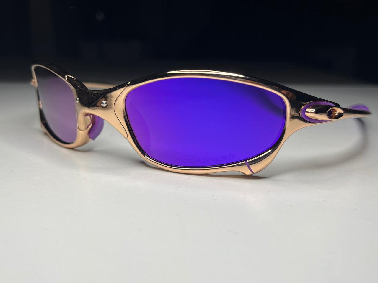 Sunglasses with purple lenses and rose gold frame on a light gray background