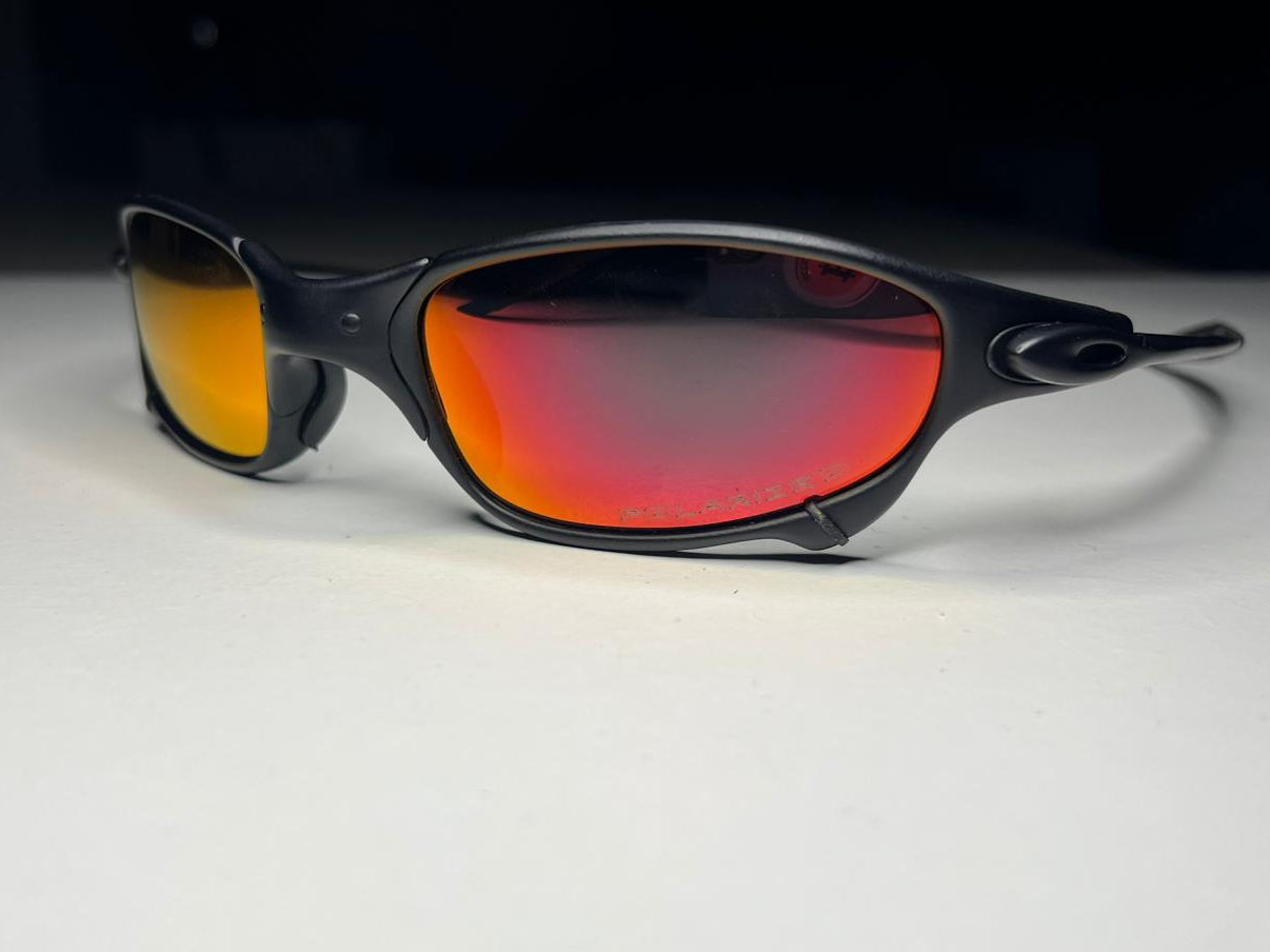 Black sunglasses with red-tinted lenses on a white surface